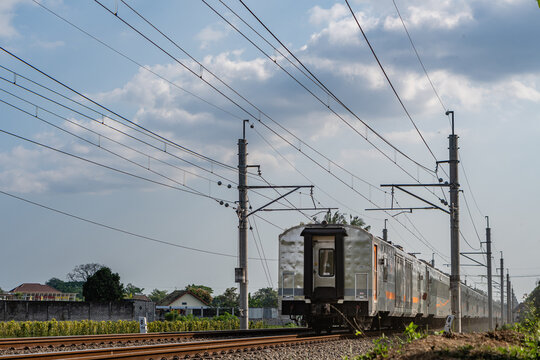 Rear view of a passenger train passing under electrical overhead lines