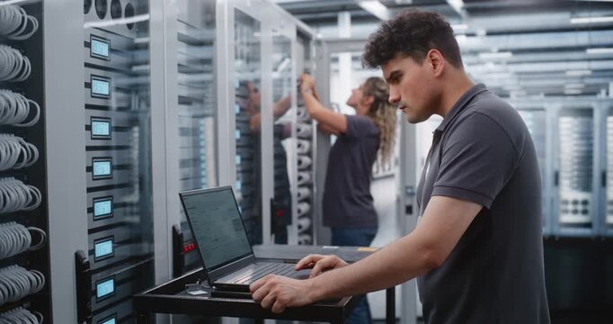 Male IT Specialist Investigates Critical Thermal Incident Using Linux Terminal, Checking System Status and Applying Emergency Console Commands. Female Colleague Services Another Server Cabinet Nearby.