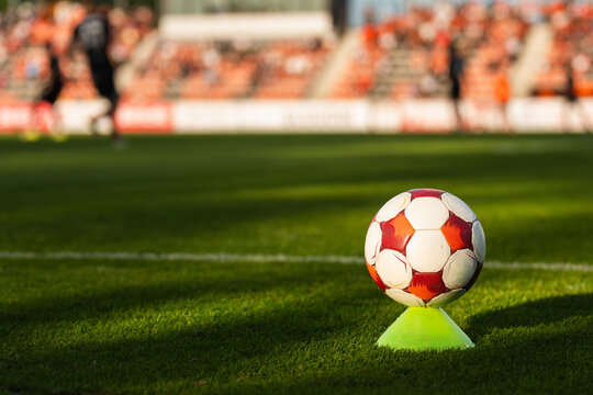 Soccer ball on a training cone near the touchline during a football match with players and stadium blurred in background