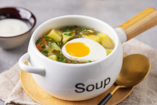 Delicious sorrel soup with leaves and egg in ceramic bowl. Spring soup with wild herbs