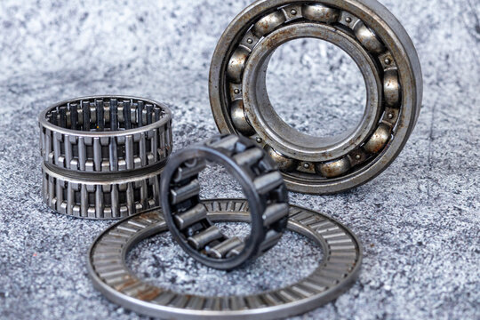 Various industrial roller and ball bearings arranged on textured concrete workshop surface.