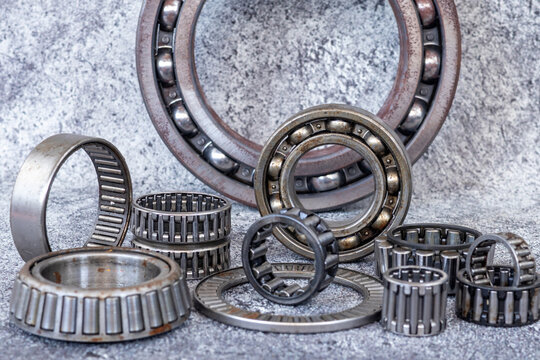 Various industrial roller and ball bearings arranged on concrete workshop floor.