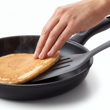 Hand flipping pancake with turner close up