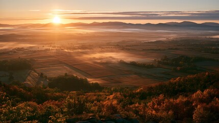 Obraz premium Scenic sunrise over a foggy valley with autumn foliage on the foreground hills