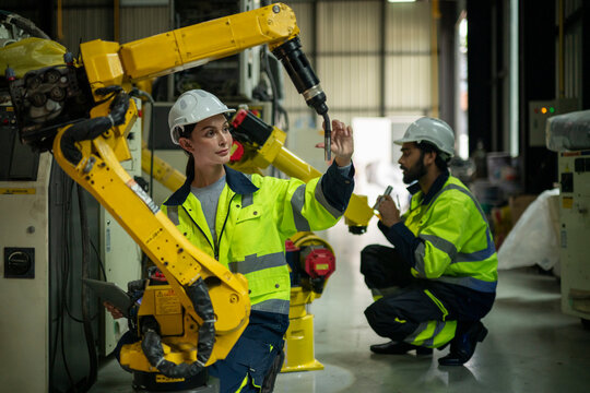 Engineers inspecting industrial robot arm in smart factory