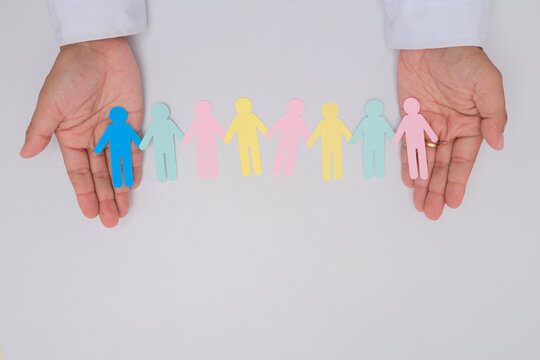 Supportive hands hold paper human cutout chain showing intergenerational community care and hopeful unity in healthcare