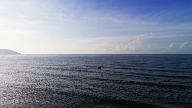 Footage shows a view of Xuan Thuy in Mui Ne, Lam Dong. The sun shines brightly over the water. A boat moves slowly on the calm sea. Waves gently roll onto the shore.