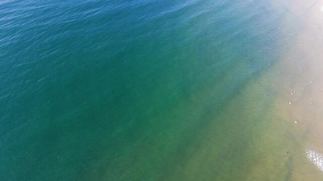 Drones capture the waves and shoreline of Xuan Thuy in Mui Ne, Lam Dong. The sun casts light over the water and beach during the day. Watch boats in the distance and enjoy the view.