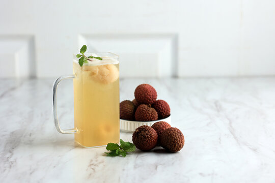 Fresh lychee drink tea beside ripe fruits.