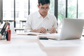 Obraz premium Professional Male Working at Desk with Laptop and Documents in Modern Office