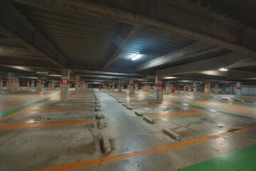 Empty underground parking garage with concrete columns and fluorescent lights © Bambi and Sunny