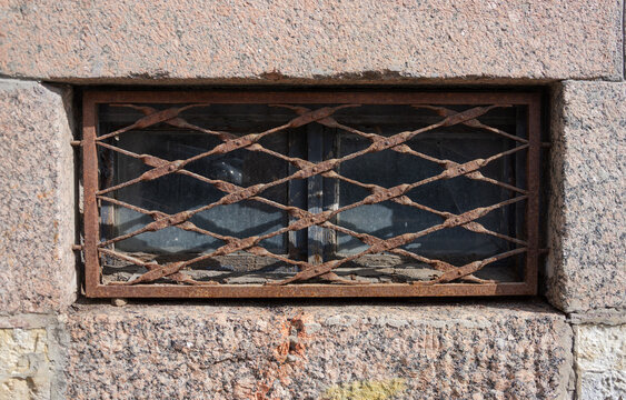 Old Basement Window With Rusty Metal Grating In Stone Wall