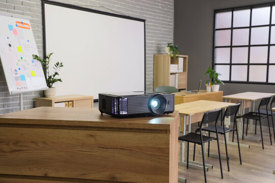 Education technology and classroom presentation, digital projector on desk in modern school room with whiteboard and chairs for learning and training