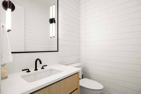 Modern powder room with wood vanity, black faucet, and white shiplap walls