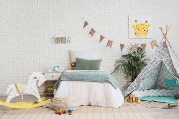 Childhood development and nursery interior, cozy bedroom with teepee tent and rocking horse for kids in a modern home with white brick wall decor © Pixel-Shot