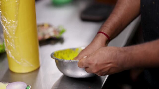 Chef Kneading Yellow Batter in Metal Bowl in Commercial Kitchen