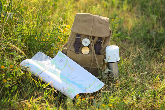 Adventure travel and exploration, backpack with compass and map in green grass for hiking trip and outdoor recreation in nature during summer season