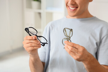 Vision correction and eyewear choice, man comparing different glasses frames for style and...