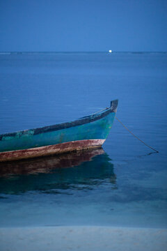 Old wooden small fisher boat in a blue quiet coastal shore scene at dusk in Maldives