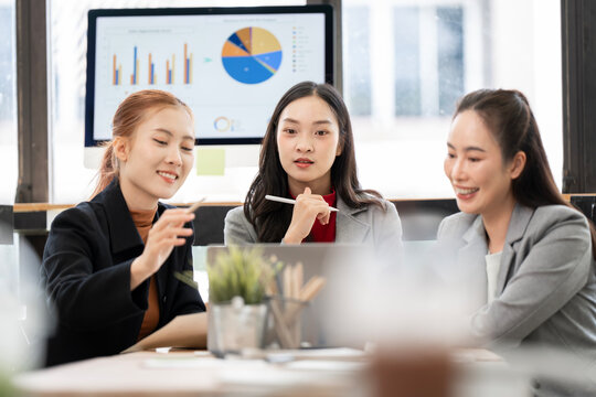 Asian Business Women Smiling and Collaborating on Financial Data