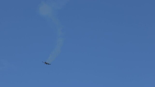 Aerobatic Stunt Plane Performing Descent with Smoke Trail in Blue Sky
