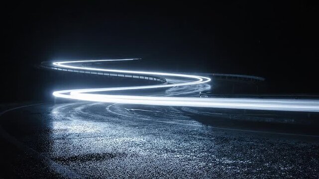 Long exposure photograph of bright blue light trails on a dark, wet, winding road at night.