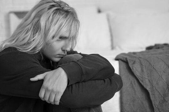 Sad young man sitting in bedroom, closeup