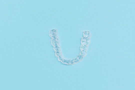 Top view of customized transparent dental teeth bite guard clear aligners for lower jaw on blue background