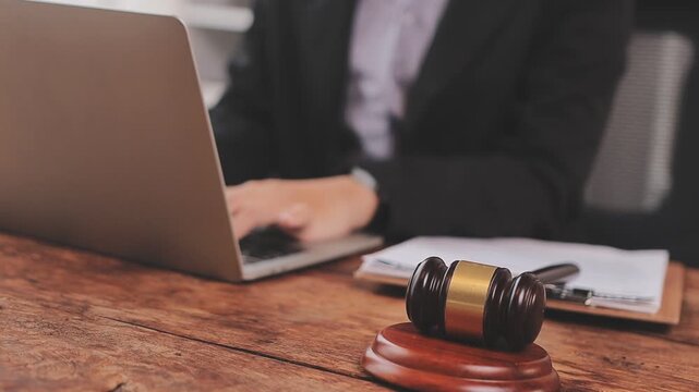 Justice and law concept. Gavel on sounding block in hand's Male judge at a courtroom, working with document law books, report the case on table in modern office.