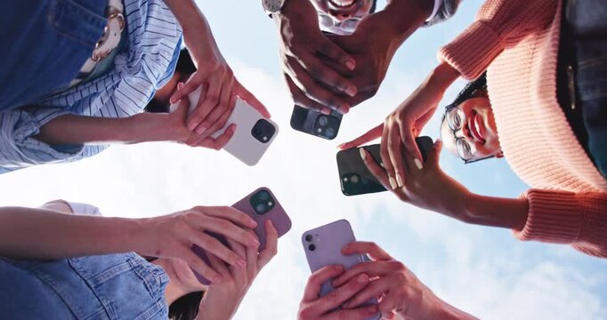 Outdoor, hands and friends with phone in circle for networking, online connection or share contact. Low angle, group and people together with mobile for communication, smile or social media app