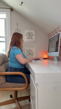 focused woman works at her desk, then suddenly she remembers something or an idea sparks