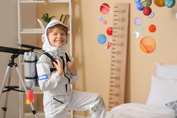 Future career and childhood dreams, happy boy in astronaut costume playing with jetpack in bedroom with space decor and telescope for science education © Pixel-Shot