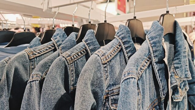 Denim Jackets on Clothing Store Rack. Row of blue denim jackets hanging on black hangers in a clothing store. Fashion retail display.