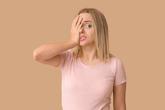 Young woman doing facepalm on beige background