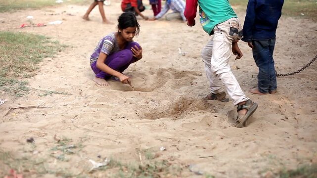 Group of children playing with marble balls outdoor in nature during summer season.