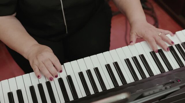 Hands of a musician play a digital keyboard during a live music performance at a wedding reception.