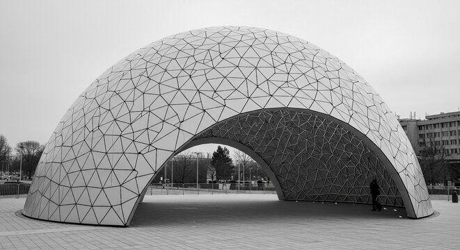Striking modern architectural pavilion featuring a geometric mesh facade and a distinctive archway.