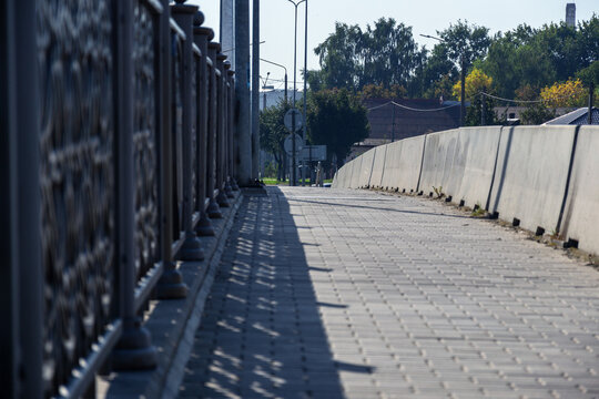 Empty bridge walkway with concrete block barrier and metal railing under morning sunlight with copy space for urban concept