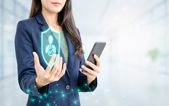 Businesswoman using a smartphone with a digital holographic shield for cybersecurity and data protection in a modern office