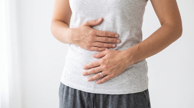 Woman holding her stomach in pain against white background, depicting abdominal discomfort, digestive issues, or health problems related to gut wellness.