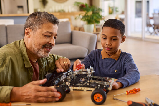 Cute little black boy builds car robot with the help of his grandfather