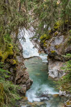Johnston Canyon stream flowing past frozen waterfall in Banff