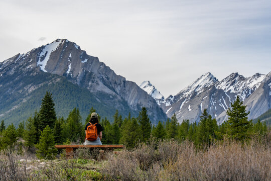 Woman sits on bench admiring snow capped mountains