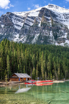 Log boathouse with canoes floating on turquoise Lake Louise in Canada