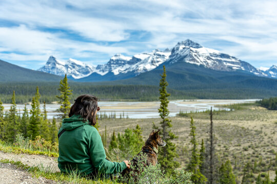 Woman and dog enjoying mountain river landscape in Banff National Park