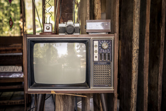 Retro old television set with an antenna no longer usable, vintage look with old camera at home.