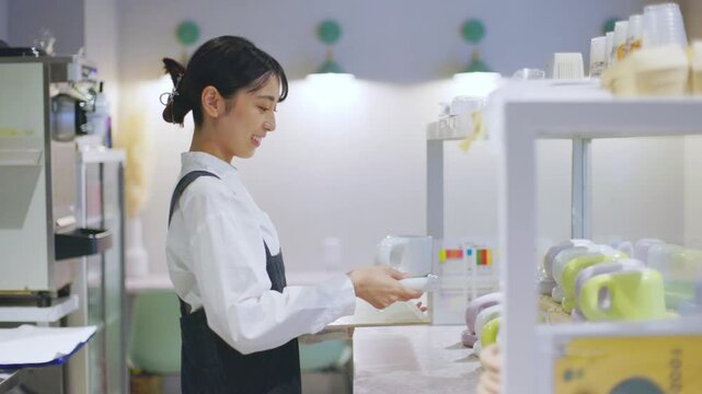 食器を載せたトレーを持ちカフェの厨房を移動する女性店員 スローモーション