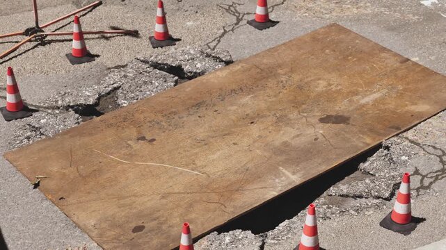 Street maintenance project, top down view of steel wooden trench plate and orange traffic cones for security. 3d animation.