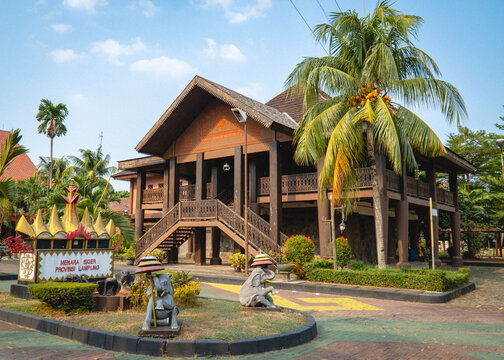 Nuwou Sessat traditional customary hall at the Lampung Pavilion in Taman Mini Indonesia Indah, Jakarta, featuring a raised wooden structure and tiled roof.
