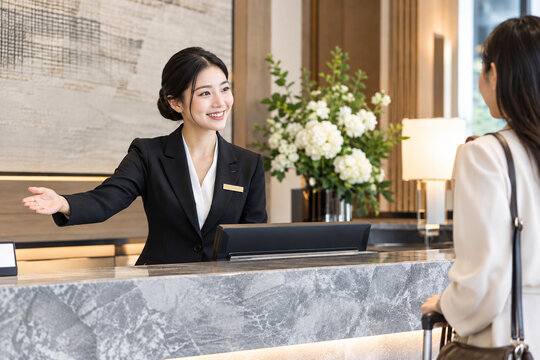 Asian hotel receptionist welcoming guest at boutique hotel front desk